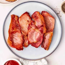 Several slices of bacon served together on a plate.