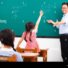 A teacher addressing a classroom and inviting questions