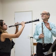 A musician playing an oboe in an orchestral woodwind section.