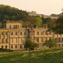A large stately manor house set in a rural landscape.