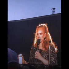 Adele performing onstage with a microphone.