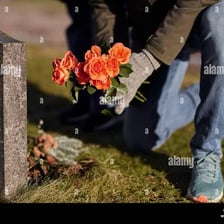 A person placing flowers at the base of a statue.