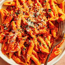A bowl of penne pasta in pink vodka sauce