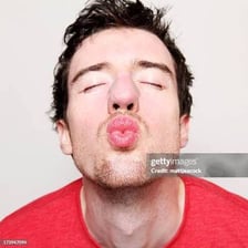 A person puckers their lips in a kissy face.