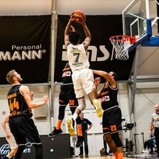 Basketball players compete on an indoor court.
