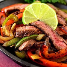 A sizzling fajita dish served in a hot skillet.