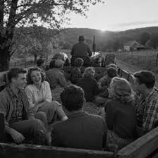 People seated on hay bales during an outdoor hayride