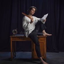 A poet writing in a notebook at a desk