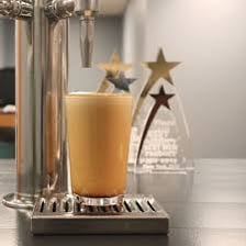 Glass of nitro cold brew with a foamy head beneath a tap