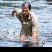 A person wading through shallow water and making splashes.