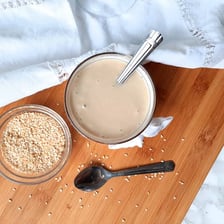 Sesame seeds beside a bowl of tahini paste