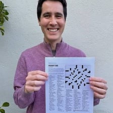 A person smiling while filling in a crossword puzzle