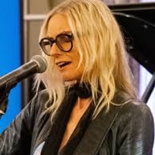 Aimee Mann performing with a guitar.
