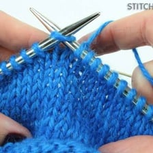 Knitting needles forming a stitch in yarn