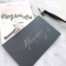 Calligraphy pens arranged beside a sample of handwritten lettering.