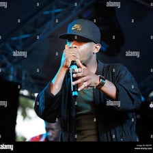 A hip-hop performer holding a microphone on stage.