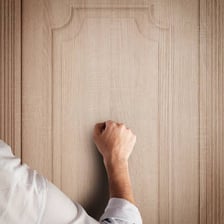 A hand knocking or rapping on a wooden door