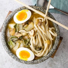 A bowl of thick udon noodles in Japanese broth