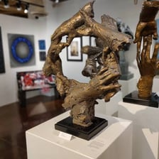 Paintings and sculptures displayed inside a gallery.