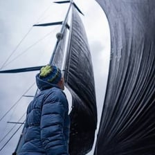 A sailboat moving across water with its sails filled by wind.