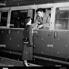 Two people waving goodbye at a train station