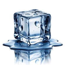 An ice cube visibly melting into a puddle of water.
