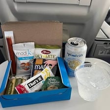 An airline snack box beside a sealed moist towelette