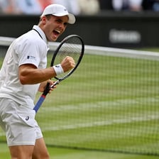 A men's professional tennis match on a grass court
