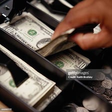 A cash register containing a stack of ten-dollar bills