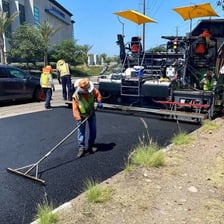A road crew laying asphalt on a road surface.