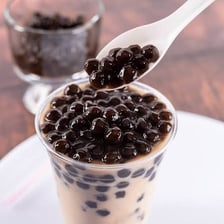 A cup of bubble tea containing round tapioca pearls.