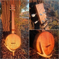 A ukulele made from figured Hawaiian koa wood beside a koa tree.