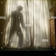 A person concealed behind a curtain.