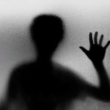 A shadowed person conveying a suspicious or secretive appearance
