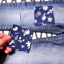 Blue jeans repaired with a fabric patch over one knee