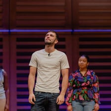An actor standing in a spotlight as the principal performer