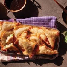 Golden fried samosas and wontons served on a plate.