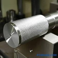 A close-up of a ridged knurled metal surface