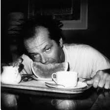 A cup of black coffee alongside a portrait of Jack Nicholson.