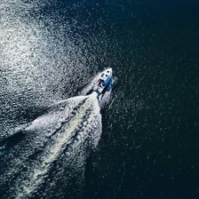 A motorboat moving across a lake and leaving a visible wake.