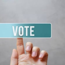 A person signaling an affirmative vote by raising a hand.