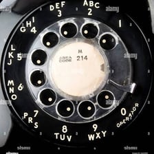 A close-up of the numbered circular dial on a rotary telephone.