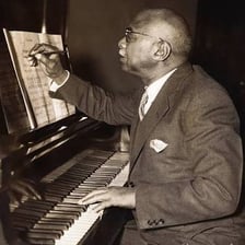 Songwriter creating music at a piano with sheet music