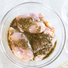 Food soaking in a seasoned marinade in a bowl.