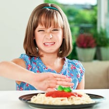A person reacting with disgust to an unpleasant food or object.