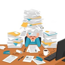 An office worker surrounded by a large stack of paperwork.