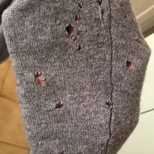 A worn sweater with holes from moth damage
