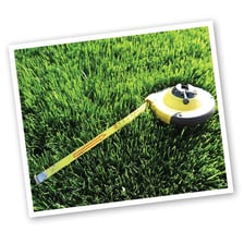 A person measuring a lawn to calculate its area for sod.