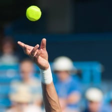 A tennis ball passing over the net toward the service box.