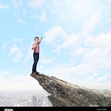 A person balancing on a high rocky ledge.
